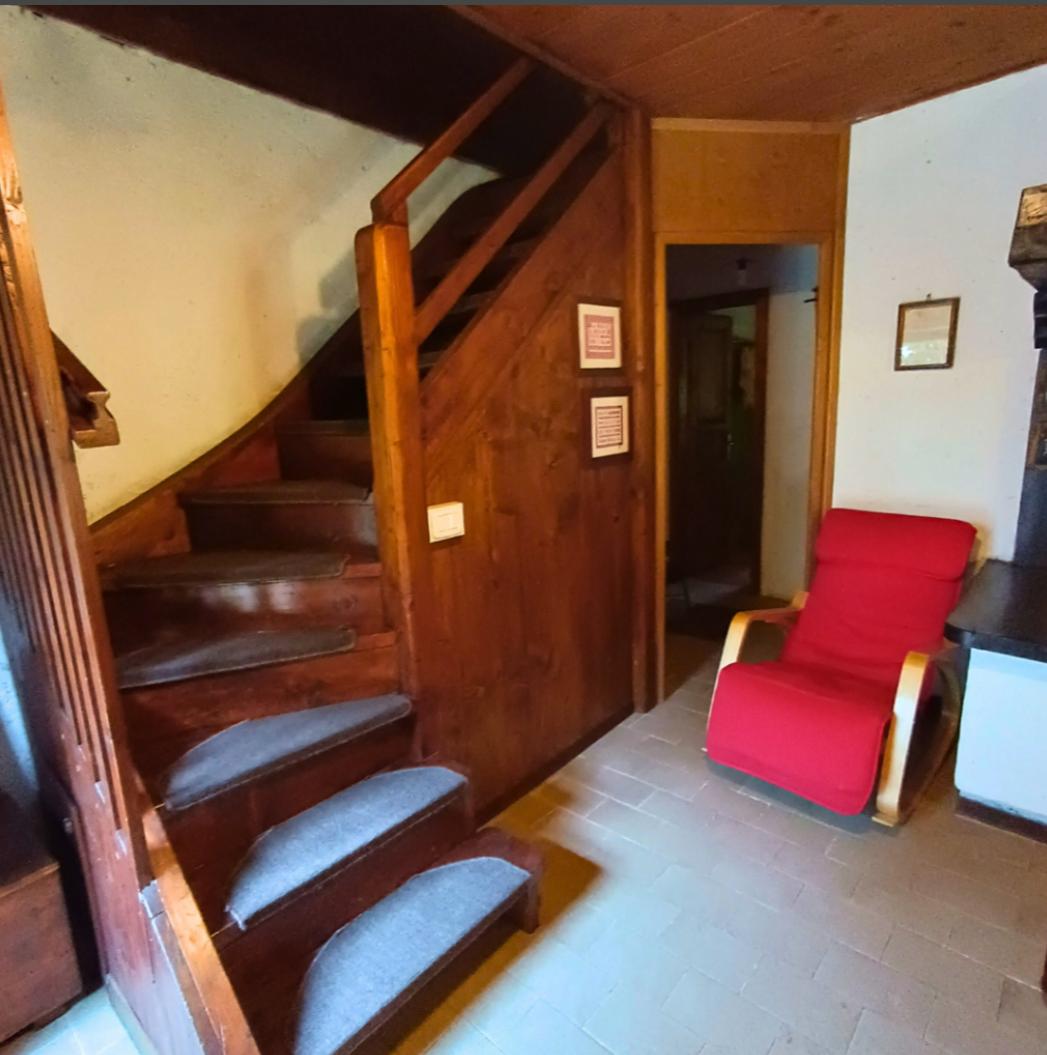 Ingresso con scala in legno e poltrona rossa